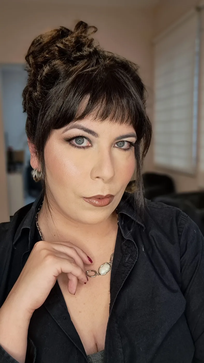 Retrato de Marcela De Simone, de franja e coque, com camisa preta, no estúdio de beleza no Juvevê